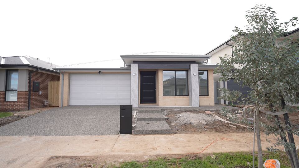 Entry of the Jagged Circuit home with stone-look pillars, dark cladding over the porch and a black front door