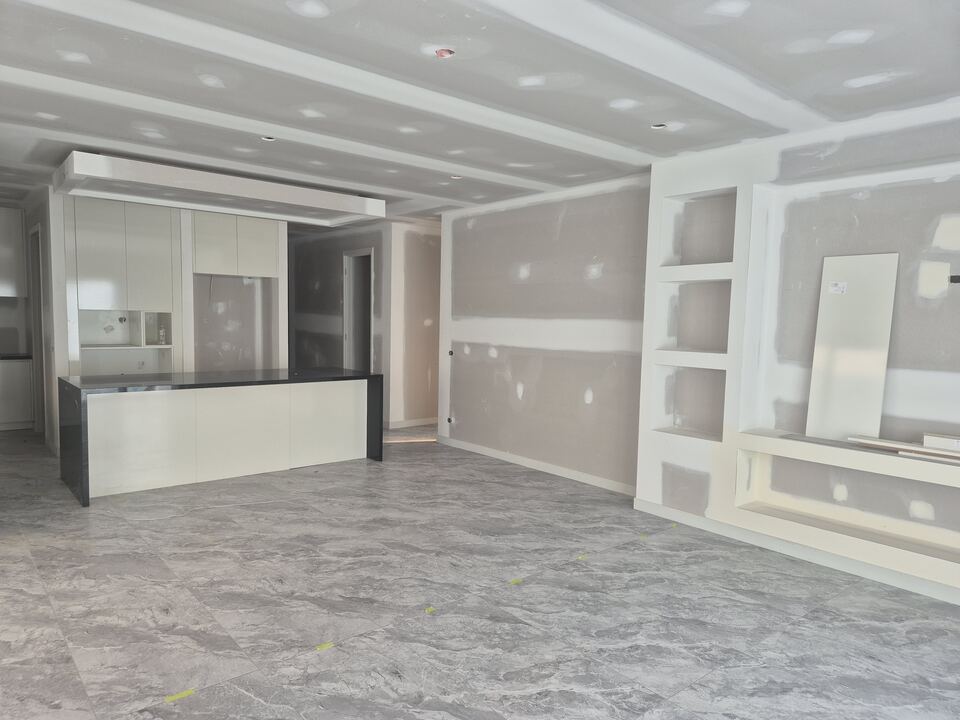 Living area at Jagged Circuit with tiles laid, kitchen joinery installed and walls ready for painting